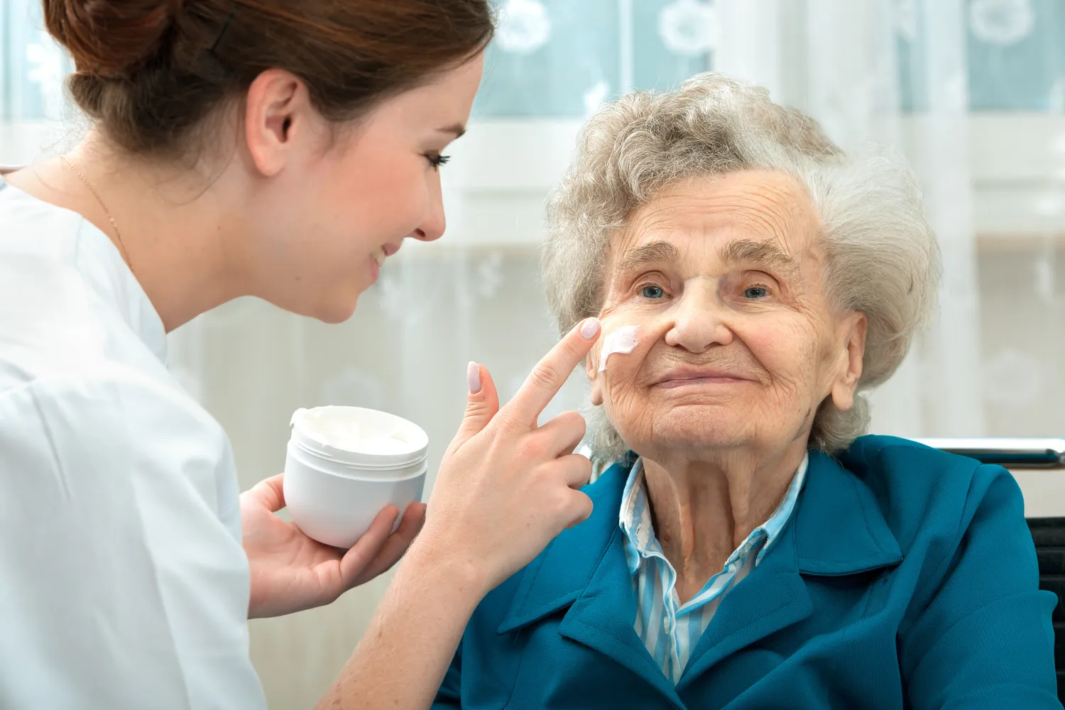 Ältere Frau wird zu Hause von einer Krankenschwester unterstützt